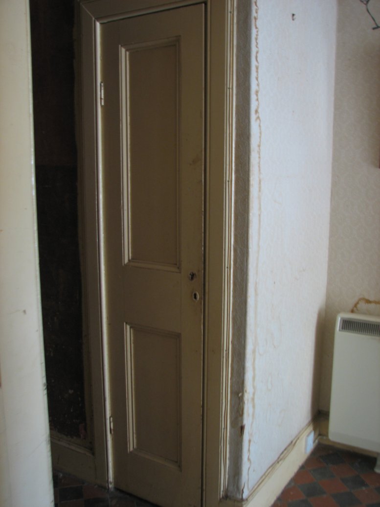 From the doorway of the sitting room, you see this narrow door into the cupboard under the stairs...